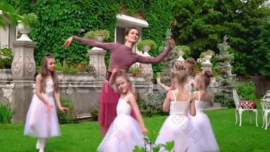 老师和小女孩一起在芭蕾舞学校的花园里跳芭蕾。 芭蕾舞演员在草坪上跳舞